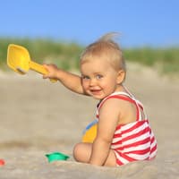 Ein Baby, das am Strand buddelt. 
