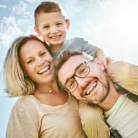 Eltern mit Kind lachen in die Kamera.