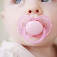 Baby mit Schnuller im Mund.