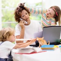 Mutter am Laptop wird von zwei Kindern genervt.