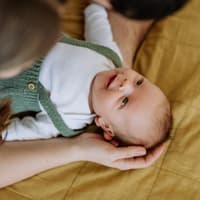 Eltern beugen sich über ihr Baby.