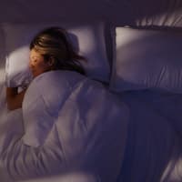 Eine Frau, die allein im Doppelbett schläft