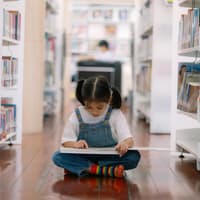 Mädchen liest in Kinderbuchhandlung.