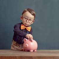 Junge steckt Geld in sein Sparschwein.