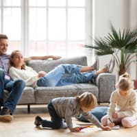 Eltern sitzen auf dem Sofa, Kinder spielen.