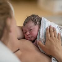 Neugeborenes liegt auf der Mutterbrust.