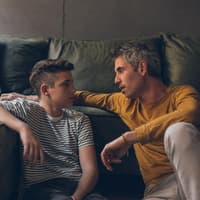 Vater unterhält sich mit jugendlichem Sohn.
