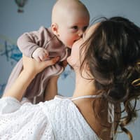 Eine Mama hebt ihr Baby hoch. 
