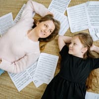Mutter und Tochter liegen zwischen Notenblättern.