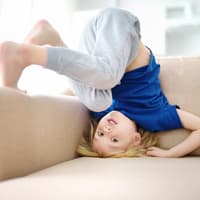Junge macht Kopfstand auf dem Sofa.