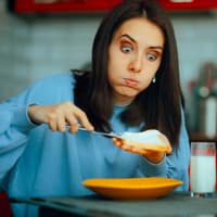 Frau schmiert sich Ricotta aufs Brot.