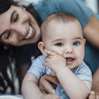 Lachendes Baby mit seiner Mutter.