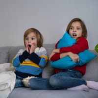 Zwei kleine Kinder fürchten sich vor dem Fernseher. 