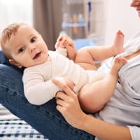 Lachendes Baby auf dem Schoß der Mutter.