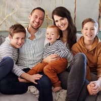 Familie mit drei Kindern sitzt auf dem Sofa.
