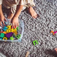 Kind räumt Spielsachen auf.