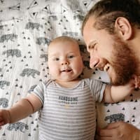 Ein Vater kuschelt mit seinem neugeborenen Baby.