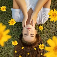 Schöne Frau liegt auf Wiese mit Blüten.