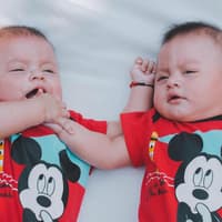Zwillingsbabys mit Micky-Maus-Body
