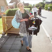 Eine Mutter trägt ihr Baby im Maxi Cosi über die Straße