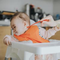 Ein Baby, das mit Brei gefüttert werden soll, dreht seinen Kopf weg.