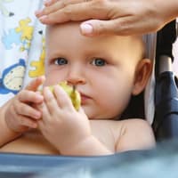 Eine Mutter fühlt die Stirn ihres Babys.