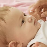 Baby bekommt Creme auf die Nase getupft.