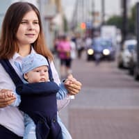 Eine Mutter trägt ihr Baby mit Blick nach vorne in der Trage 