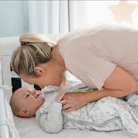 Eine Mama bringt ihr Baby ins Bett.