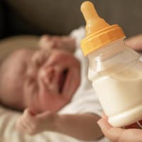 Schreiendes Baby und Milchflasche