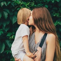 Mama küsst Ohr ihres Kindes.