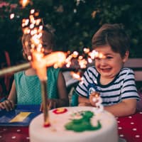 Kinder mit Geburtstagstorte mit Wunderkerze