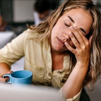 Erschöpfte Frau mit Kaffeebecher.