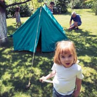 Familie baut ein Zelt im Garten auf.