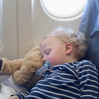 Ein kleiner Junge schläft im Flugzeug. 