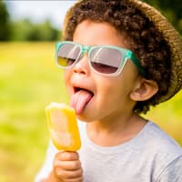 Ein Junge leckt an einem Eis aus Fruchtsaft. 