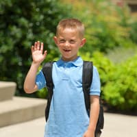 Kleiner Schuljunge winkt zum Abschied.