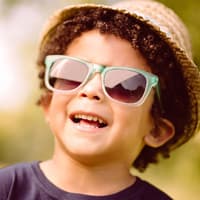 Eine Sonnenbrille schützt empfindliche Kinderaugen.