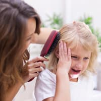 Mutter bürstet ihrem Kind die Haare.