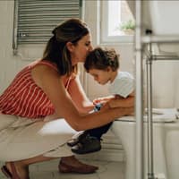 Mutter begleitet Kleinkind auf die Toilette.
