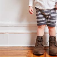 Kleinkind mit viel zu großen Schuhen.