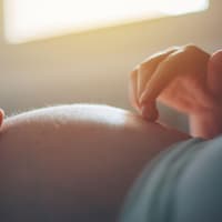 Schwangere berührt ihren Bauch mit Händen.