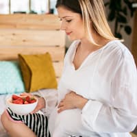 Schwangere Frau mit einer Schale Erdbeeren in der Hand