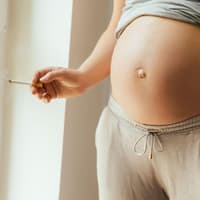 Frau mit Babybauch und Zigarette