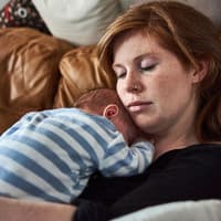 Mama schläft mit Baby auf ihrem Bauch.