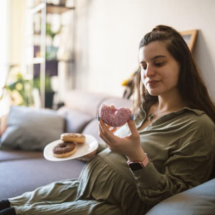 Eine Frau isst Donuts in der Schwangerschaft