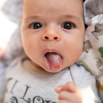 Ein kleines Baby streckt seine Zunge raus.