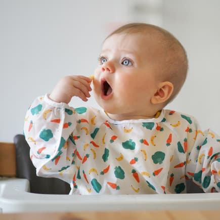 Baby steckt sich etwas zu Essen in den Mund. 
