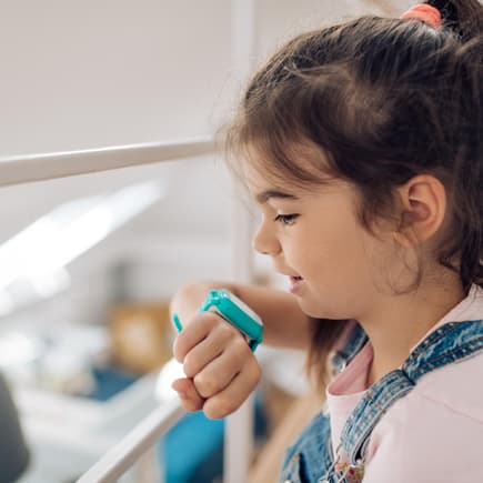 Junges Mädchen schaut auf ihre GPS-Uhr am Handgelenk. 