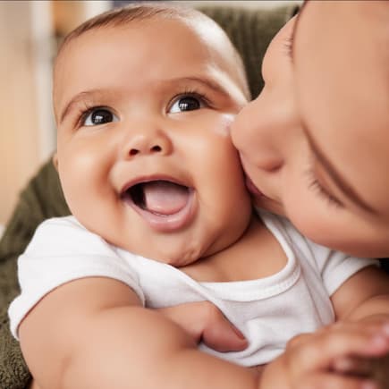 Ein Baby, das von seiner Mama geküsst wird.